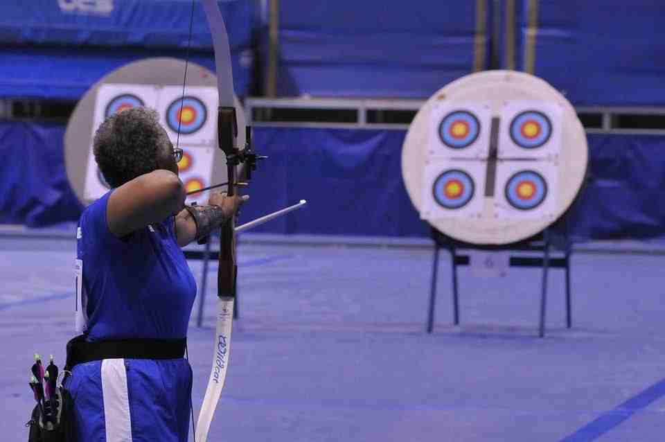 A woman aiming with a recurve bow learning how to aim a recurve bow with sights